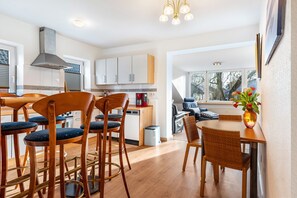 A modern kitchen with wooden bar stools, a dining table, and a view of the outside. - Holiday flat in Schulensee near Kiel (Molfsee)