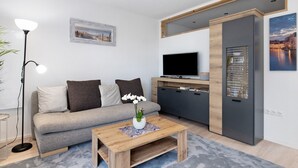 A modern living room with a sofa, coffee table, TV, and cabinets. - Apartment 'König' with Mountain View, Shared Terrace and Wi-Fi (Lustenau)