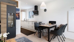 A modern kitchen with a dining area, a large window, and a view of a cityscape. - Apartment 'König' with Mountain View, Shared Terrace and Wi-Fi (Lustenau)