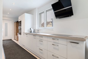 Eine moderne Küche mit weißen Schränken, einer Edelstahl-Arbeitsplatte und einem eingebauten Backofen.