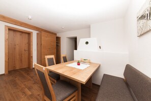 A dining area with a wooden table, four chairs, a sofa, and a refrigerator.