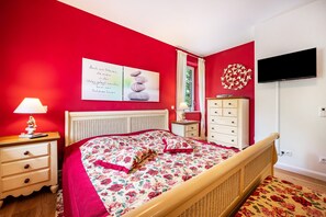 Un dormitorio con cama, cómoda, televisor y un cartel en la pared.