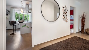 A modern interior with a round mirror, a kitchen area with a dining set, and a view through a doorway. - Apartment Kronsberg with Sauna, Private Garden, Wi-Fi and Air Conditioning (Bösel)