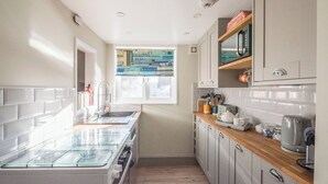 Eine kleine Küche mit Einbauofen, Spüle und Fenster für natürliches Licht.