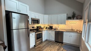 Une cuisine moderne avec des armoires blanches, des appareils en acier inoxydable et un plancher en bois.