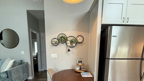 Une cuisine moderne avec un réfrigérateur en acier inoxydable, une table à manger en bois avec quatre chaises et un luminaire suspendu au-dessus.