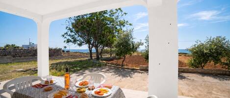 A table set for dining with a view of the sea and trees.