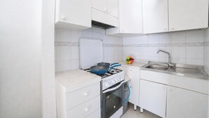 A compact kitchen with white cabinets, a gas stove, a sink, and a small oven. - La Conchiglia di Torre Vado with Sea View, Morciano di Leuca, Italy (Morciano di Leuca)