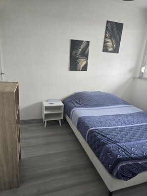 Un dormitorio con una cama, una mesita de noche, un armario de madera y dos obras de arte colgadas en la pared.