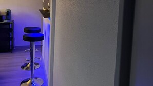 A hallway with a bar area featuring three bar stools and a neon sign on the wall. - Le Cocoon / Free parking / Wifi (Belfort)