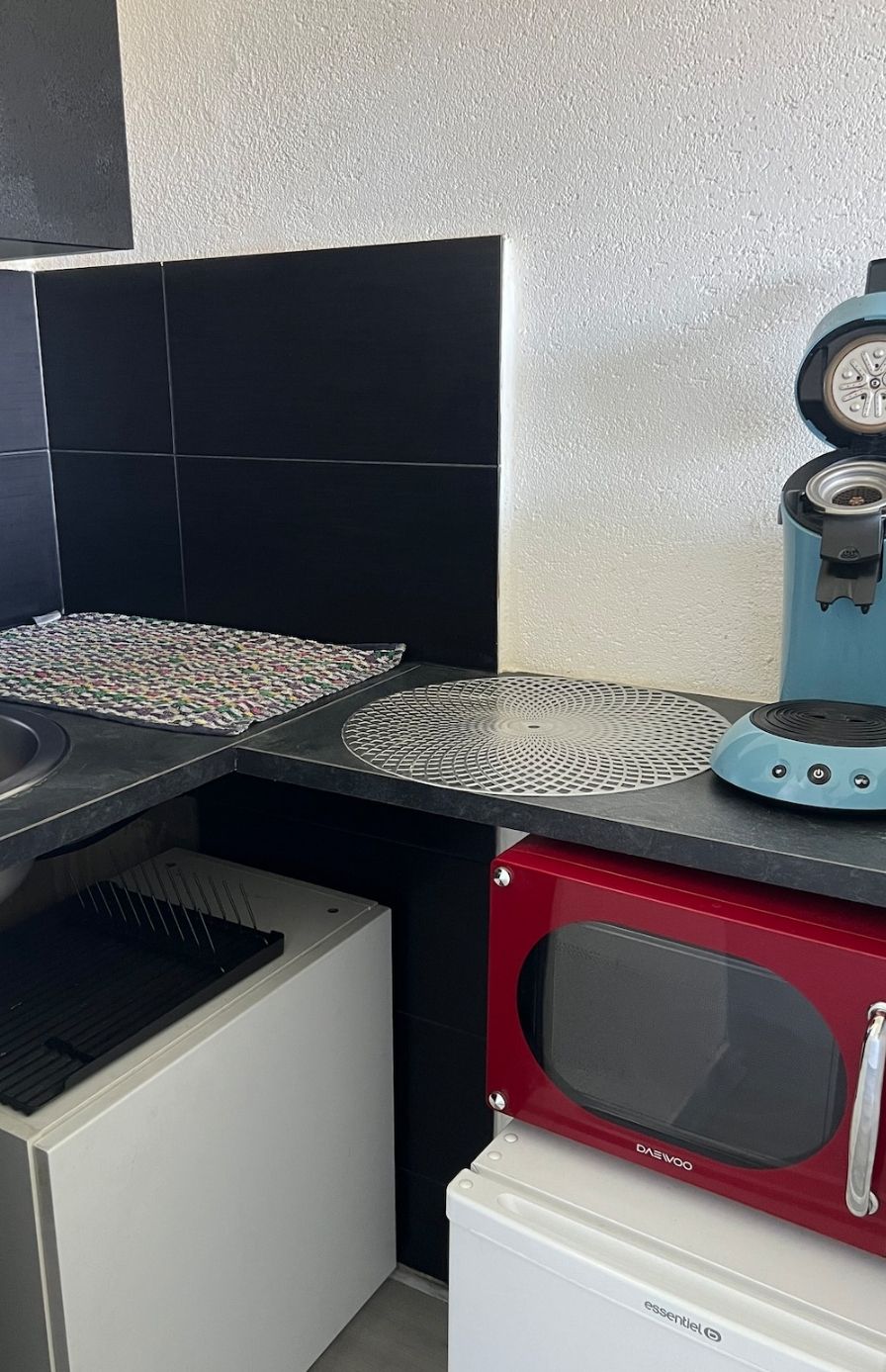 Una cucina con un forno a microonde, un forno rosso e un lavello.