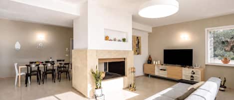 A modern living room with a fireplace, dining area, and a large TV.