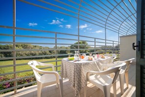 A terrace with a table set for two, overlooking a green landscape.