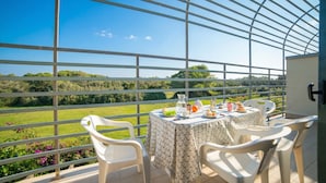 A balcony with a table set for two, overlooking a green landscape.