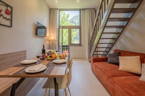 Una sala de estar moderna con comedor, una escalera y vistas a zonas verdes.