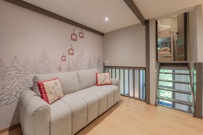 Un salon moderne avec un canapé, une fresque murale, un balcon et une fenêtre.