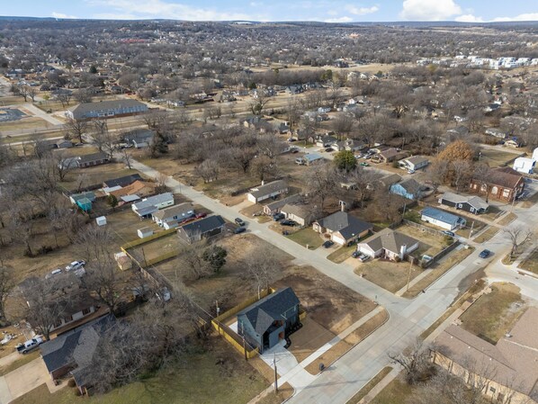 An aerial view of a residential area with houses, streets, and a large building with a blue roof. - Modern Masterpiece in Downtown Tulsa-Sleeps 6 (Tulsa)
