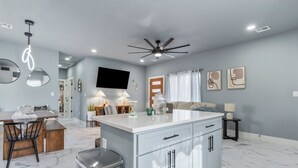 A modern kitchen with a central island, white cabinetry, and a ceiling fan. - Modern Masterpiece in Downtown Tulsa-Sleeps 6 (Tulsa)