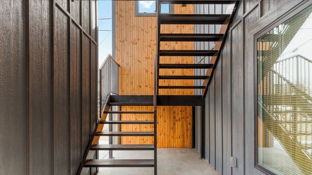 A narrow hallway with a wooden wall and a metal staircase. - Modern Masterpiece in Downtown Tulsa-Sleeps 6 (Tulsa)