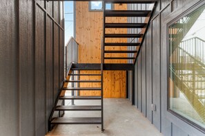 A narrow hallway with a wooden wall and a metal staircase. - Modern Masterpiece in Downtown Tulsa-Sleeps 6 (Tulsa)