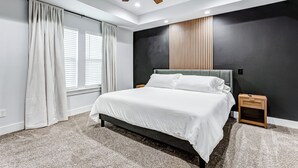 Een moderne slaapkamer met een groot bed, een plafondventilator en een nachtkastje.