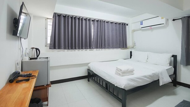 Una habitación de hotel con una cama, un escritorio con tetera, televisión y aire acondicionado.