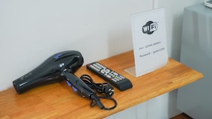 Un secador de pelo, un control remoto y un cartel con las credenciales de WiFi sobre una mesa de madera.