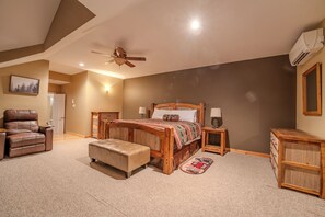 Ein Schlafzimmer mit einem großen Bett, einem Ledersessel, einem Nachttisch aus Holz und einer Holzkommode.