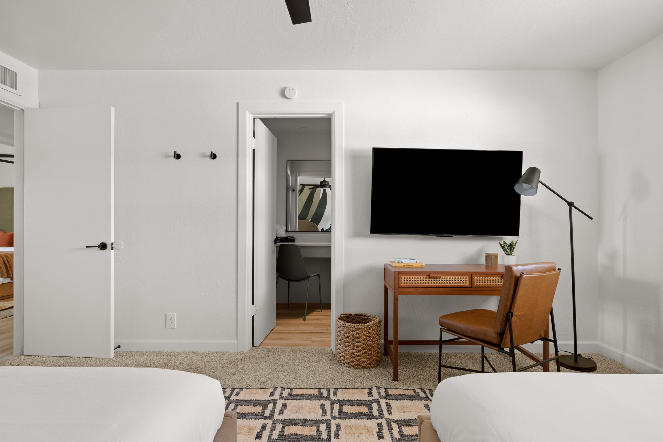 Una habitación de hotel con una cama, un escritorio con una silla, un televisor y una lámpara.