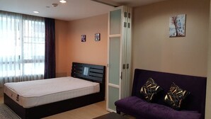 A bedroom with a bed, a sofa, a small table, and a window with curtains. - Cosy room like home, The Central Bangkok Station (Krung Thep Maha Nakhon)