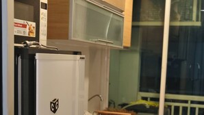 A compact kitchen with a white refrigerator, wooden cabinets, and a microwave. - Cosy room like home, The Central Bangkok Station (Krung Thep Maha Nakhon)