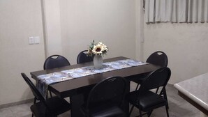 En matplats med ett bord, stolar, en takfläkt och en vas med blommor.
