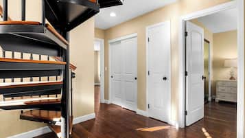 Un interior moderno con una escalera de caracol, pisos de madera y puertas blancas.