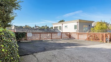 A private parking area with a gated entrance, a building with a flat roof, and a clear blue sky.