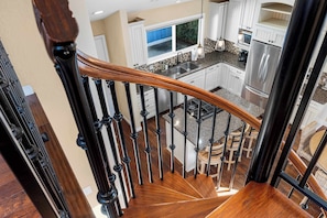A modern kitchen with white cabinets, a stainless steel refrigerator, and a granite countertop. - Capitola Village Home - Free Parking & Sleeps 8! (Capitola)