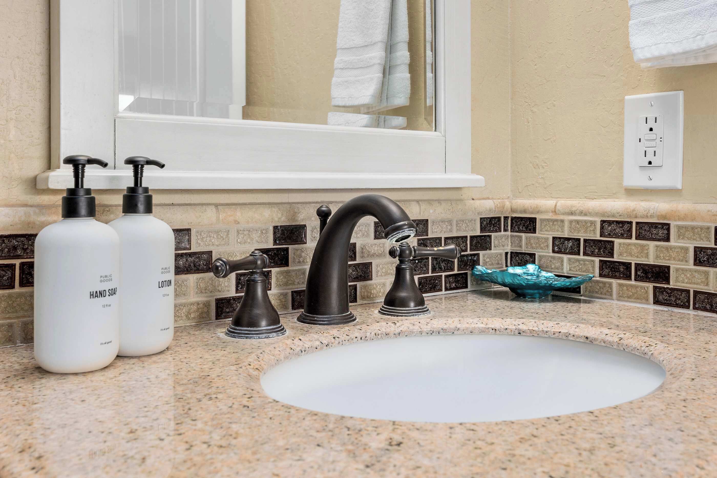 A bathroom with a sink, two hand soap bottles, a faucet, and a mirror.