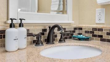 A bathroom with a sink, two hand soap bottles, a faucet, and a mirror.