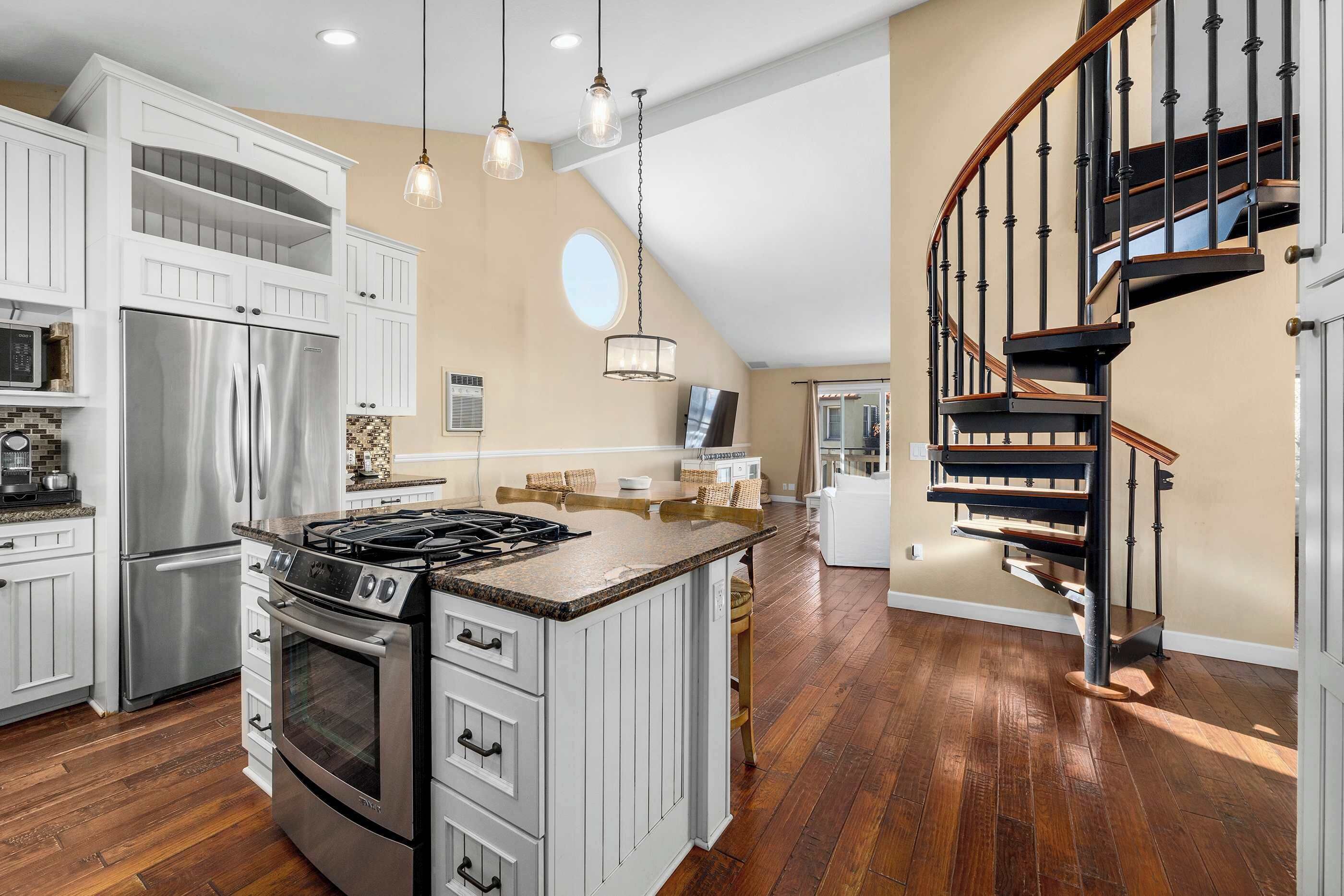 Una cocina moderna con una isla central, electrodomésticos de acero inoxidable y una escalera de madera.