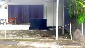 Un bâtiment avec une grande porte bleue, une voiture garée et une barrière à chaîne.