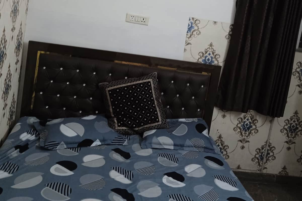 A bedroom with a tufted headboard, a patterned bedspread, and three hexagonal wall decorations.