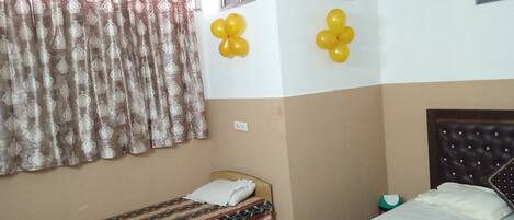 Un dormitorio con dos camas, una ventana, aire acondicionado y globos amarillos en la pared.