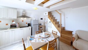 A modern kitchen with white cabinets, a built-in oven, and a dining area with a wooden table and chairs.