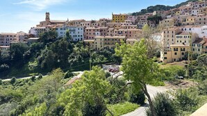 A hillside town with colorful buildings, a prominent clock tower, and a road winding through the area.