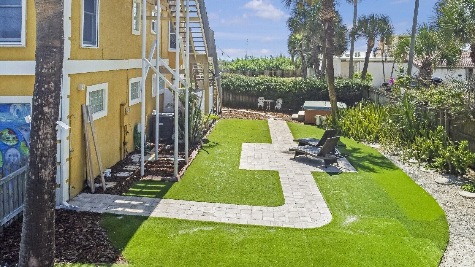 Ein Wohngebiet mit gepflasterter Terrasse, Sitzgelegenheiten im Freien und einem gepflegten Rasen.