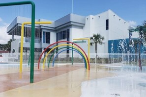 Un parque infantil con arcos de colores y un edificio de fachada blanca al fondo.