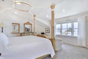 Un dormitorio con una cama grande, un aparador, un espejo y una ventana con vistas.