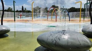 Ein Wasserspielplatz mit mehreren Wasserstrahlen und einem zentralen Steinobjekt.