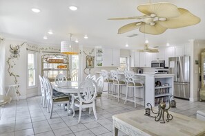 A spacious kitchen with white cabinetry, a central island, and a ceiling fan.