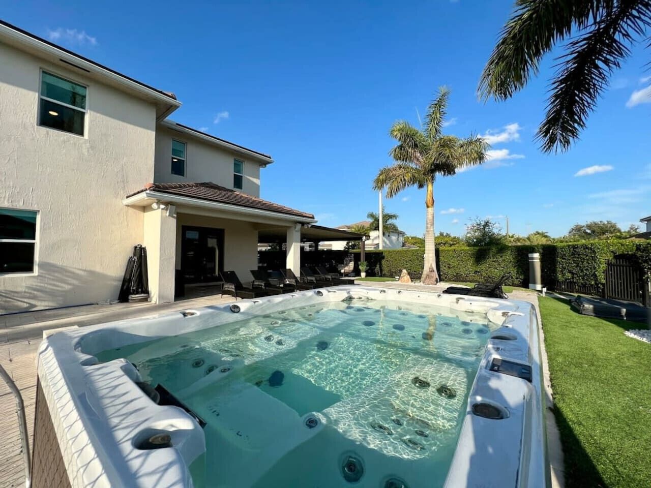 A hot tub in a backyard with a house in the background.