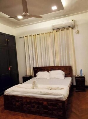 A neatly made bed with white linens, a wooden headboard, and a bedside table with a bottle.